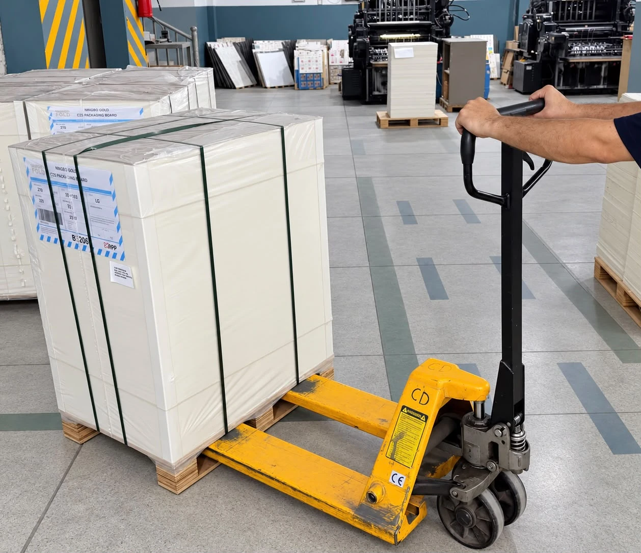 A pallet lifter carrying paperboard to production.