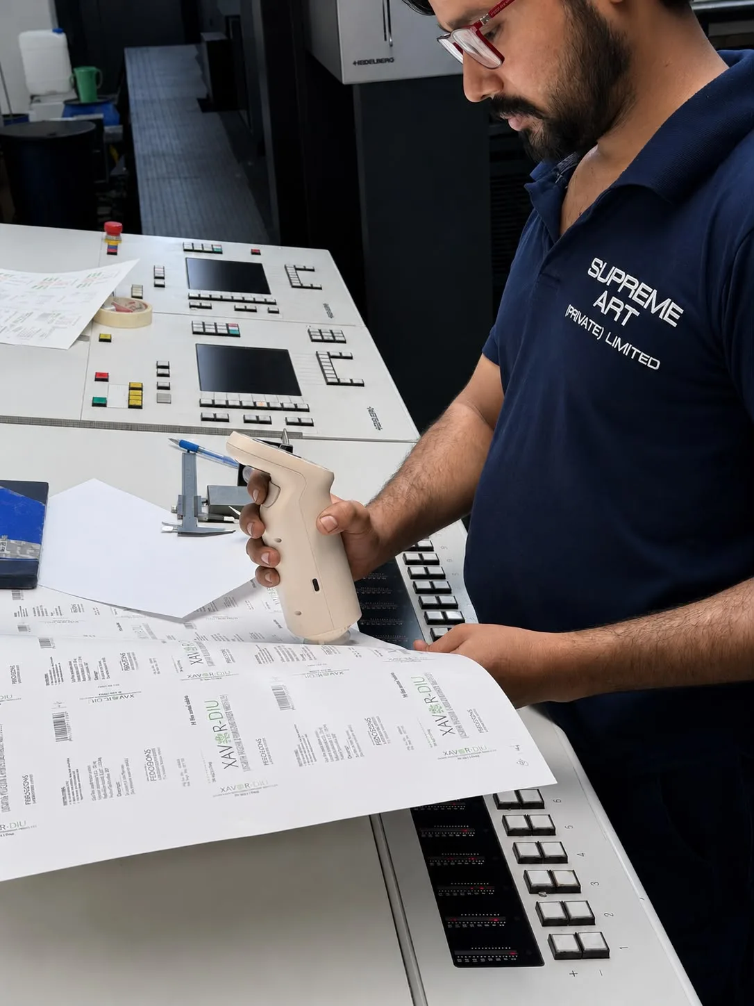 Operator measuring a printed sheet with a handheld spectrophotometer.